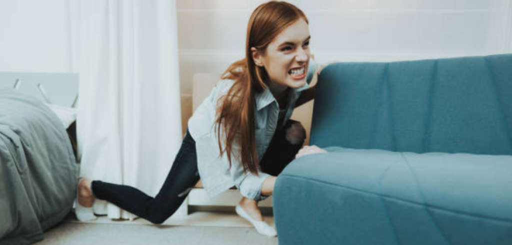 Woman struggling to push a sofa